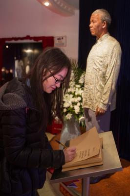 游客在上海杜莎夫人蠟像館曼德拉蠟像邊的吊唁本上寫下唁詞，寄托哀思
